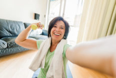 Energetic woman holding a small dumbbell while exercising on the floor of her home